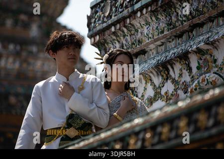 BANGKOK, THAILAND, 12. JAN 2026: Junges Paar in traditioneller thailändischer Kleidung posiert für ein Foto, aus einem tiefen Winkel Stockfoto