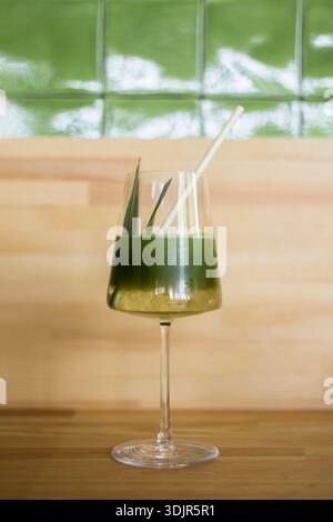 Japanische Eismatcha Latte, grüner Tee mit Milch, Sojamilch, traditionelle Matcha-Werkzeuge, mit Bambusstroh im Glas auf hölzernem Hintergrund. Stockfoto