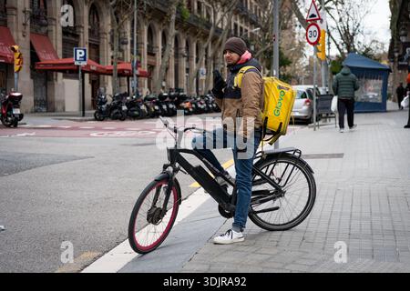 Barcelona, Spanien. Januar 2026. Ein Migrant wird als Fahrer für die Lieferfirma Glovo im Stadtzentrum gesehen. Die spanische Regierung unter der Leitung von Premierminister Pedro Sánchez genehmigte eine außerordentliche Regularisierung, die rund 500.000 Migranten ohne Papiere legale Aufenthaltsrechte und Arbeitsrechte gewährte - ein historischer Schritt, der auf Inklusion, Menschenrechte und wirtschaftliche Integration abzielte. (Foto: Davide Bonaldo/SIPA USA) Credit: SIPA USA/Alamy Live News Stockfoto