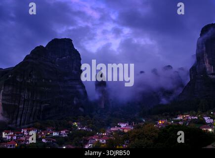 Das Dorf Kastraki unter den hoch aufragenden Meteora-Felsformationen, umgeben von dramatischen Wolken und Abendnebel, Thessalien, Griechenland Stockfoto