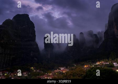 Das Dorf Kastraki unter den hoch aufragenden Meteora-Felsformationen, umgeben von dramatischen Wolken und Abendnebel, Thessalien, Griechenland Stockfoto