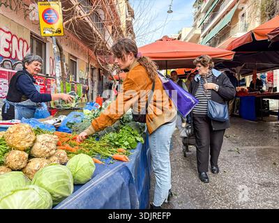 Kallidromiou Street Market (Λαϊκή Αγορά Καλλιδρόμιου). Die Käufer kaufen frische Produkte, einschließlich Kohl und Karotten, im traditionellen Athen Bauernhaus Stockfoto