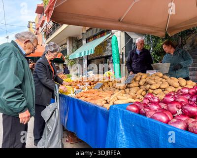 Kallidromiou Street Market (Λαϊκή Αγορά Καλλιδρόμιου). Athen, Griechenland. Szene, in der Käufer Kartoffeln und Zwiebeln auf dem wöchentlichen Bauernmarkt kaufen Stockfoto