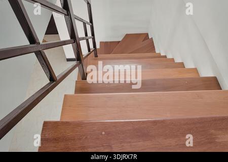 Eine moderne Holztreppe mit elegantem Metallgeländer aus nächster Nähe. Die Treppen sind aus poliertem Holz, die nach oben führen in einem sauberen, minimalistischen Stockfoto