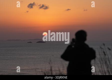 Zhoushan, Stadt Zhoushan in der ostchinesischen Provinz Zhejiang. Januar 2026. Ein Besucher fotografiert den Sonnenuntergang auf der Insel Huaniao im Komitat Shengsi, Stadt Zhoushan in der ostchinesischen Provinz Zhejiang, 28. Januar 2026. Quelle: Huang Zongzhi/Xinhua/Alamy Live News Stockfoto