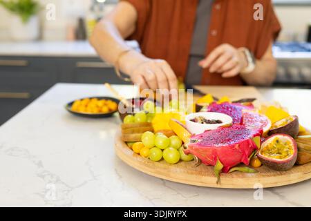 Farbenfrohe Drachenfrüchte und Trauben ruhen auf runden hölzernen Servierbrettern auf Marmorarbeitsfläche Stockfoto