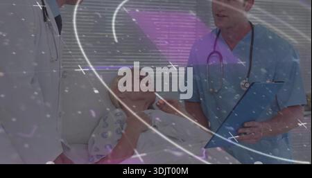 Liegender Patient mit gemustertem Kleid Pflege vom Personal im Krankenhauszimmer blau schrubbt Klemmbrett Stockfoto
