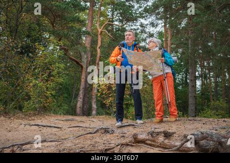Wandertourismus. Senior Paar Mann Frau, die auf einer Karte auf Papier sucht, genießt Wanderungen im Wald. Glückliche alte Leute Backpacker Wanderer genießen Wandern Wandertourismus Aktivurlaub Schönheit der Natur Stockfoto