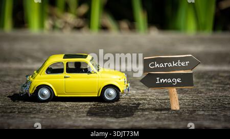 Ein Bild mit einem Wegweiser, der in zwei verschiedene Richtungen auf Deutsch zeigt. Eine Richtung ist nach Zeichen, die andere nach Bild. Stockfoto