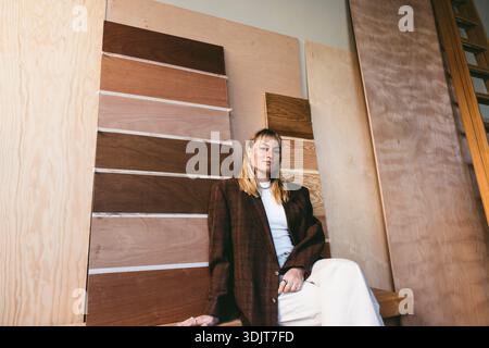 Porträt einer selbstbewussten Designerin, die im Büro an verschiedenen Holzmustern sitzt Stockfoto