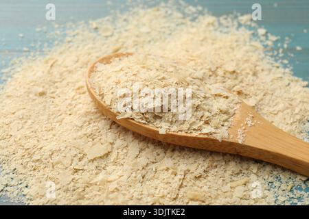 Trockene Hefeflocken im Holzlöffel auf dem Tisch, Nahaufnahme Stockfoto