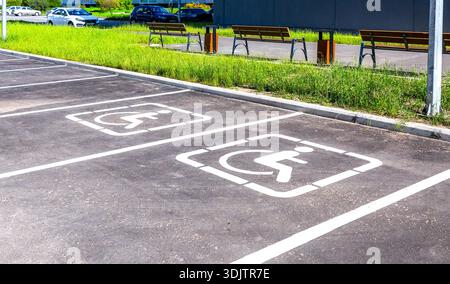 Parkplätze mit Behindertenschildern und Markierungslinien auf Asphalt auf dem Hof des Appartementhauses Stockfoto