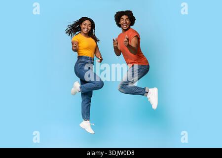 Glückliche afroamerikanische Liebhaber feiern den Erfolg auf Blau Stockfoto