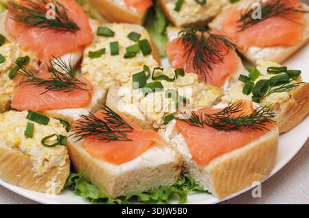 Offene Sandwiches mit Räucherlachs und Frischkäse mit Kräutern. Frische Vorspeise auf Brotscheiben zubereitet. Präsentation von Hausmannskost. Stockfoto