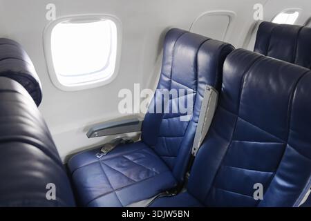 Leere Fluggastsitze in der Kabine von Verkehrsflugzeugen. Blaue Ledersessel am Fenster in der Economy Class. Moderner Innenraum für Flugreisen. Stockfoto