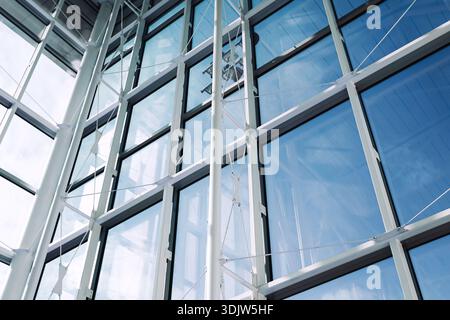 Moderne Glasfassade des Bürogebäudes mit Stahlkonstruktion. Abstrakter Architekturhintergrund mit Reflexionen und geometrischen Linien. Stockfoto