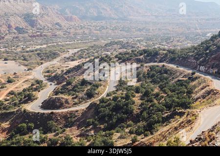 Gewundene Bergstraße von oben, die durch felsige Hügel und grüne Vegetation führt. Landschaftlich reizvolle Luftlandschaft in ländlichem Gelände mit Kurven. Stockfoto