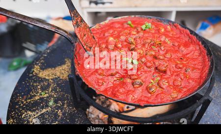 Schnecken kochen in Tomatensauce über offenem Feuer Stockfoto