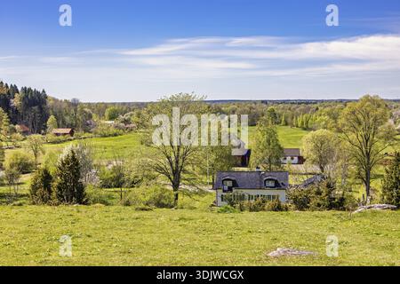 Schöner Landschaftsblick mit Wiesen und Feldern und Wohnhäusern auf dem Land an einem schönen sonnigen Frühlingstag, Schweden Stockfoto
