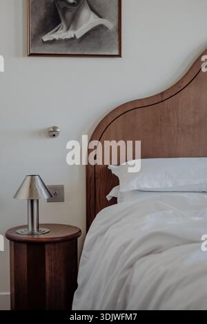 Luxuriöses Hotelbett in elegantem Schlafzimmer, hochwertige weiße Bettwäsche und Kissen, Komfort und moderne Inneneinrichtung. Stockfoto