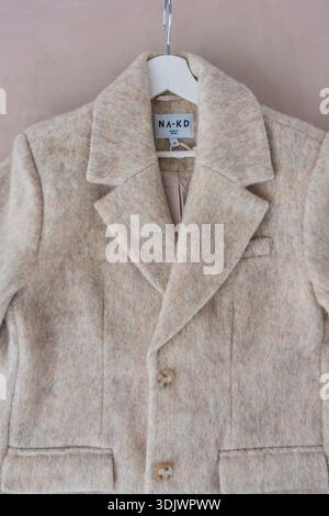 Prag, Tschechische Republik - 16. September 2024: NA-KD beige Wollmischmantel auf Kleiderbügel, sichtbares Etikett Stockfoto