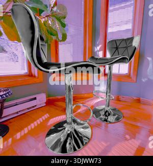 Das Innere einer modernen Küche, Dinette, Sonnennische, zeigt Chrom-Sockel, Barstühle und Pflanzen im Sonnenlicht und Schatten von großen Fenstern. Stockfoto