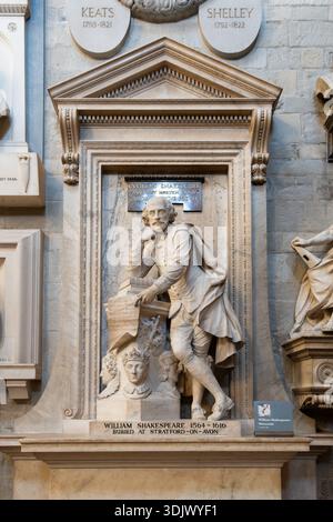 Eine Gedenkstatue von William Shakespeare steht in der Westminster Abbey in London. Es zeigt ihn mit einer Schriftrolle. Besucher kommen, um ihren Respekt zu erweisen und die Kunstwerke zu bewundern. Stockfoto