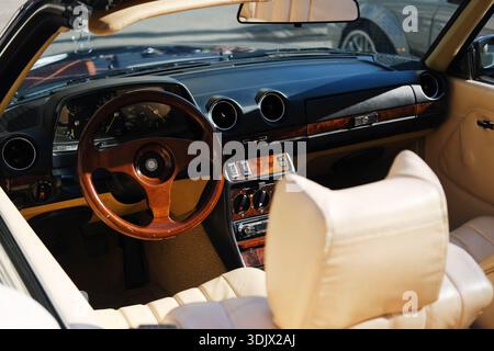 Minsk, Weißrussland - 10. April 2025: Luxuriöser Innenraum mit Ledersitzen und Holzdetails, mit klassischem Lenkrad und modernem Design Stockfoto