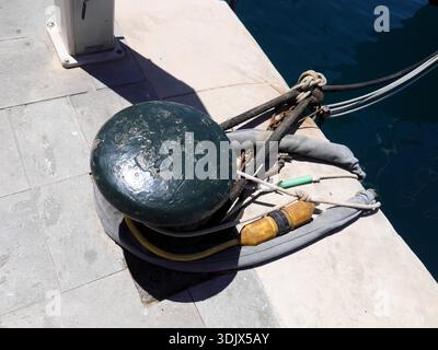 An einem großen schwarzen Schiffspoller an einem Dock oder Pier befestigte Seile Stockfoto