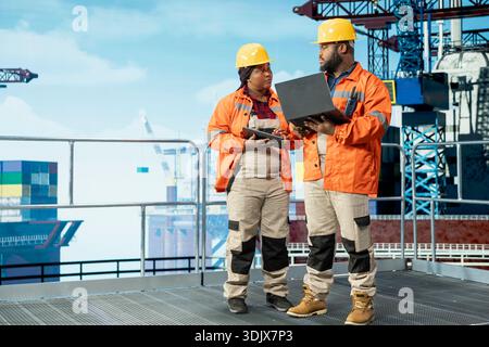 Ein Team von Experten für die Automatisierung von Offshore-Plattformen konfiguriert Schiffsmanagementsysteme für eine effizientere Ölförderung. Teamkollegen von Bohrgeräten führen eine Analyse des Meeresbodens mit einem Laptop durch Stockfoto