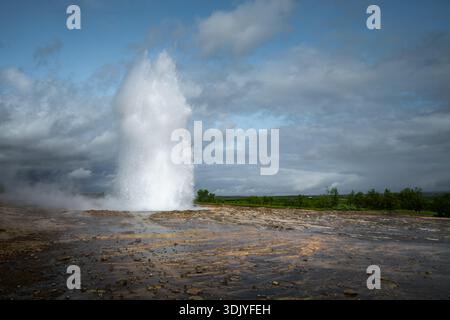 Wasser bricht aus Strokkur Geysir in Islands geothermischer Region. Stockfoto