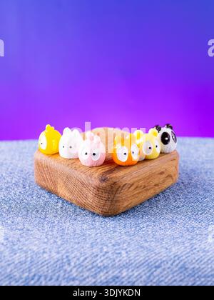 Eine Nahaufnahme einer Reihe von farbenfrohen, bezaubernden Tierfiguren im Kawaii-Stil, die auf einer Holzbühne platziert werden Stockfoto