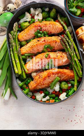 Im Ofen gebratener Lachs mit grünen Bohnen und Spargel zum Osterbrunch oder Abendessen auf hellem Hintergrund. Draufsicht. Stockfoto