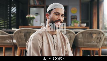 Muslime, Lächeln und Mann im Haus mit Porträt, positiver Einstellung oder Ruhe in der Ramadan-Tradition. Islam, glückliche oder männliche Person im Wohnzimmer mit Frieden Stockfoto