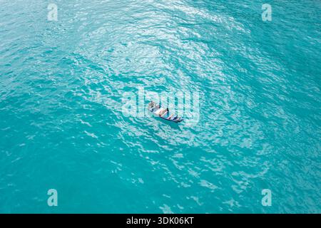 Aus der Vogelperspektive eines kleinen Bootes, das auf dem türkisfarbenen Meer liegt, bildet einen auffälligen Kontrast zu den weiten Wasserflächen Kalleesa, Socotra und Jemen. Stockfoto