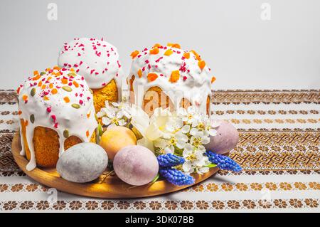 Traditioneller Osterkuchen mit Glasur, getrockneten Früchten und Samen sowie bemalten Eiern und Frühlingsblumen Stockfoto