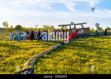 Kappadokien, Türkei - 18. Mai 2025: Touristen feiern erfolgreiche Heißluftballonlandung mit Champagner in der Nähe einer entleerten Hülle in Kappadokien Stockfoto