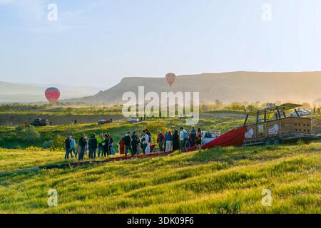 Kappadokien, Türkei - 18. Mai 2025: Eine Gruppe von Personen genießt traditionelle Zeremonie nach dem Flug mit Getränken neben Ballonkorb und Anhänger Stockfoto