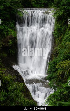 Langzeitaufnahme der Sandiaoling-Wasserfälle in Taiwan, mit seidenweichem fließendem Wasser, das über Felsen in üppiger Waldvegetation fließt und eine Ruhe schafft Stockfoto