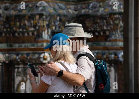 BANGKOK, THAILAND, 15. JAN 2026: Seniorenpaar mit Rucksäcken, die zusammen stehen und ein Selfie machen, Haut, Haarstruktur, Rückansicht Stockfoto