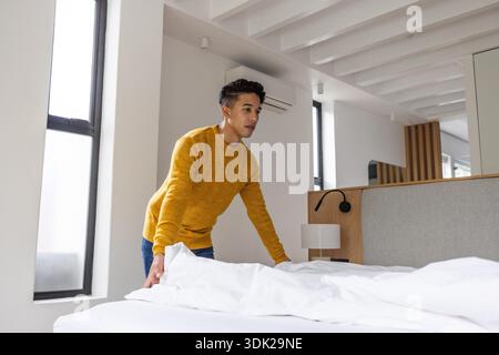 Asiatisches Bett in hellem, modernem Schlafzimmer mit weißer Bettwäsche, grauem Kopfteil und geteilter Klimaanlage. Minimalistisch, modern, gemütlich, innen, Lifestyle, Wohnort, tagsüber || Modell veröffentlicht Stockfoto