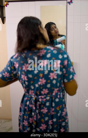 Eine Frau steht vor einem Spiegel und bereitet sich auf eine Veranstaltung vor. Stockfoto