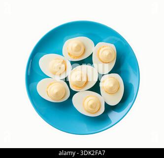 Gekochte Hühnereier mit Mayonnaise auf einer blauen Platte isoliert auf weißem Hintergrund, Draufsicht. Stockfoto