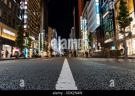 Tokio, Japan - 3. August 2024: Eine Niedrigwinkelaufnahme fängt die beleuchteten Straßen von Ginza, Tokio, bei Nacht ein und zeigt das pulsierende Stadtbild. Stockfoto