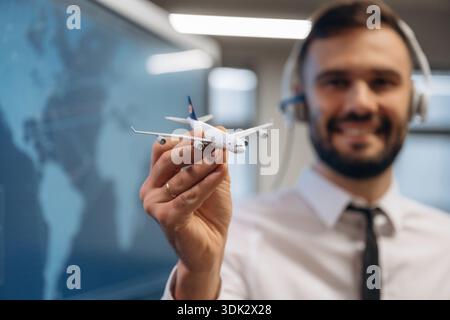 Fröhlicher Gesichtsausdruck. Der Mann hält ein Spielzeugflugzeug in der Fluggesellschaft. Stockfoto