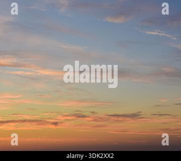 Ein ruhiger Nachmittagshimmel mit einem Farbverlauf aus Blau und Orange mit zarten, verstreuten Wolken für die Natur. Stockfoto