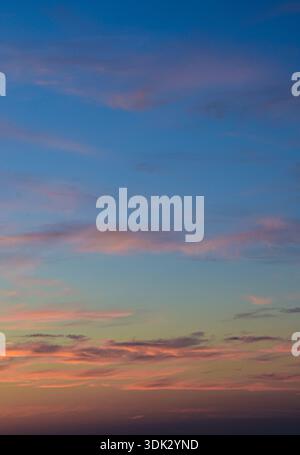 Wunderschön gestaltete orange und rosa Wolken vor einem tiefblauen Himmel während der goldenen Stunde eines späten Nachmittags. Stockfoto