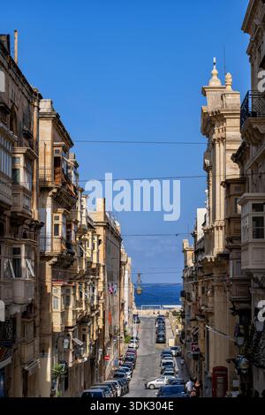 Stadt Valletta auf Malta, Häuser entlang einer schrägen Straße zum Meer. Stockfoto