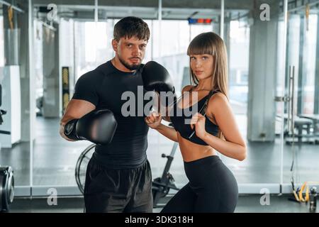 Vorderansicht, stehend und posierend. Mann und Frau sind zusammen im Fitnessstudio. Stockfoto