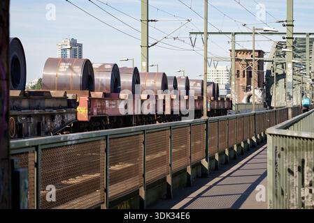Köln, Deutschland 19. August 2025: Güterzug mit schweren Stahlspulen über die historische Südbrücke in Köln. Städtische Logistik und ra Stockfoto